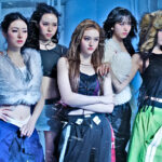 Screenshot from MEOVV’s “BURNING UP” MV teaser showing group members in sporty Y2K-inspired outfits, fast cuts, dynamic poses, headbands and beanies visible, high-energy retro vibe, digital single releasing Oct 14 6 PM KST.